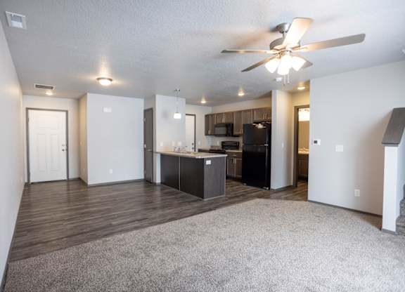A spacious living room with a kitchen area in the background.