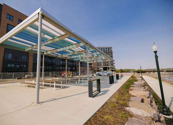 A modern outdoor seating area with a glass roof and a stone wall.