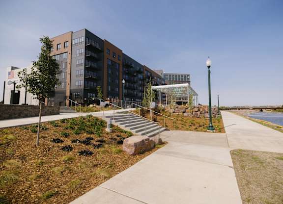 A modern building with a flag on the left side and a lamp post on the right.