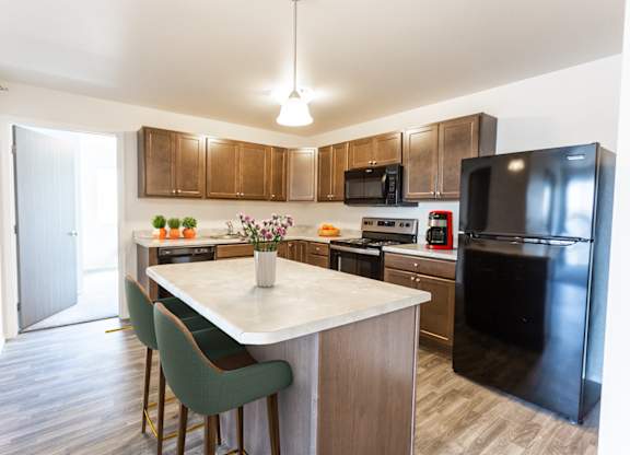 A kitchen with a black refrigerator and a white island.