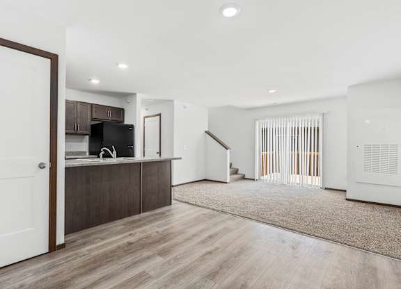 A modern kitchen with a white door and wooden flooring.