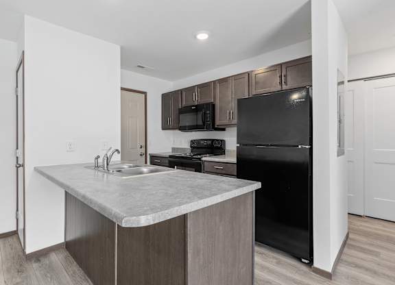 A kitchen with a black fridge and microwave.