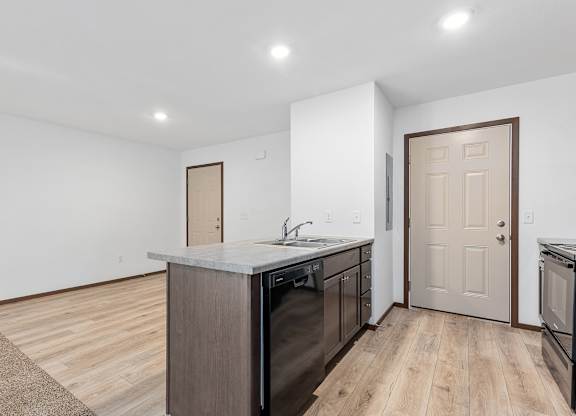 A kitchen with a white countertop and wooden floors.