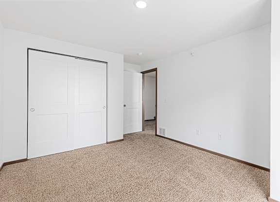 A carpeted room with a white door and a white wall.