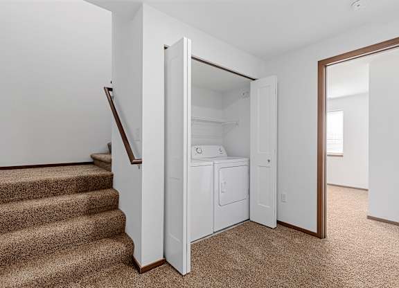 A white closet with a mirror is open to a hallway.
