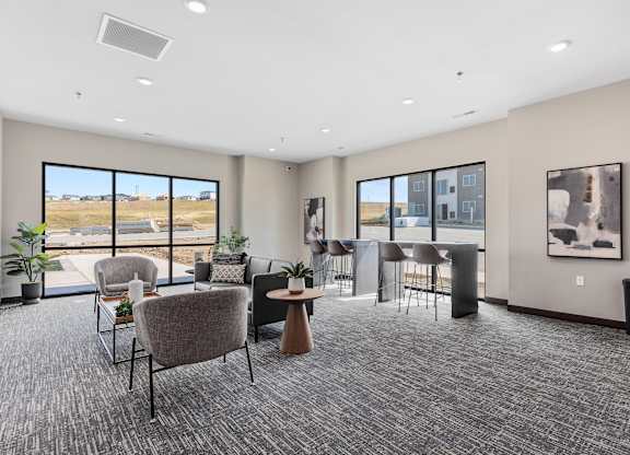 A room with grey carpet and a large window overlooking a field.
