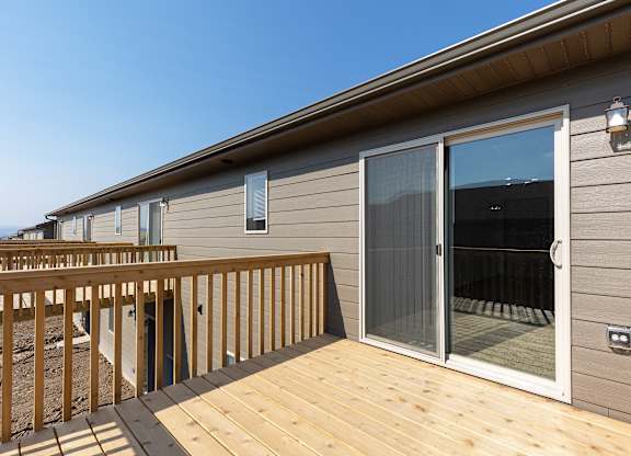 A wooden deck leads to a sliding glass door.