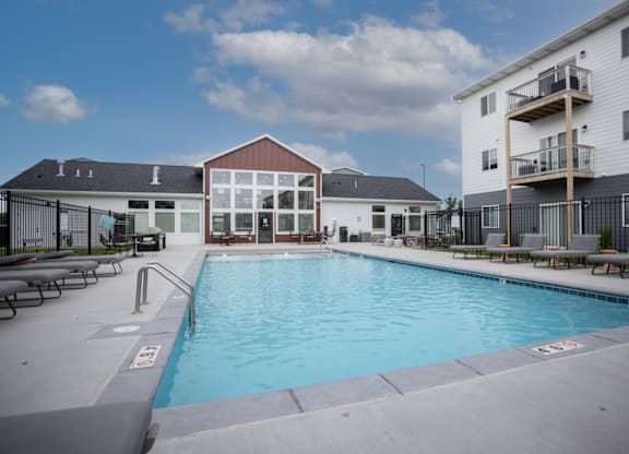 A swimming pool in front of a building with a black fence around it.