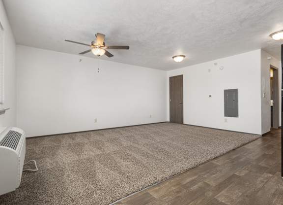 A room with a ceiling fan and a carpet on the floor.