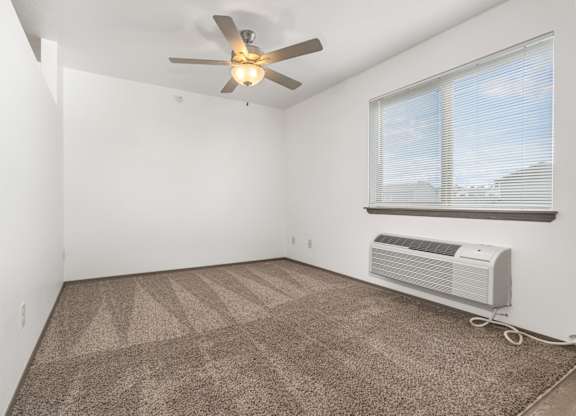 A room with a ceiling fan and a window with blinds.