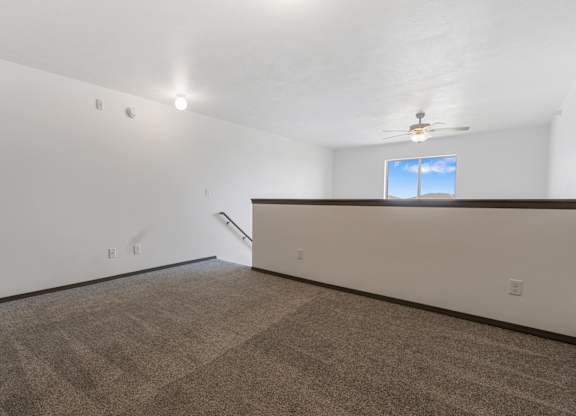 A room with a carpeted floor and a window with a view of the sky.