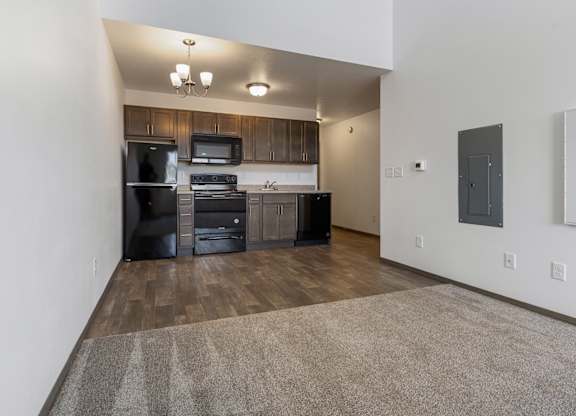 A kitchen with dark wood cabinets and black appliances.