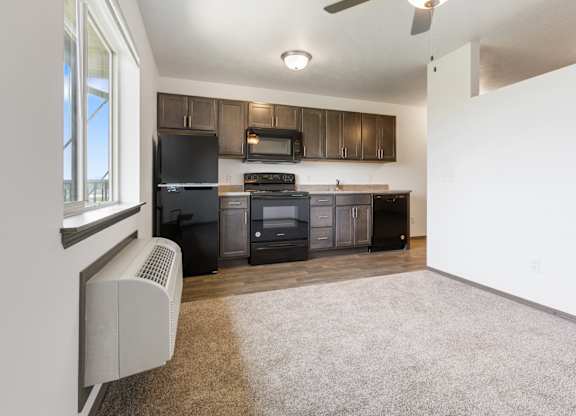 A kitchen with black appliances and brown cabinets.