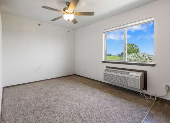 A room with a ceiling fan and a window showing a view of the outside.