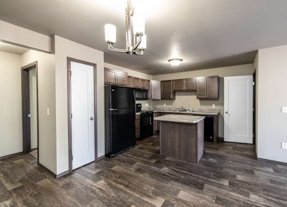 a kitchen with black appliances and wood flooring in a new home