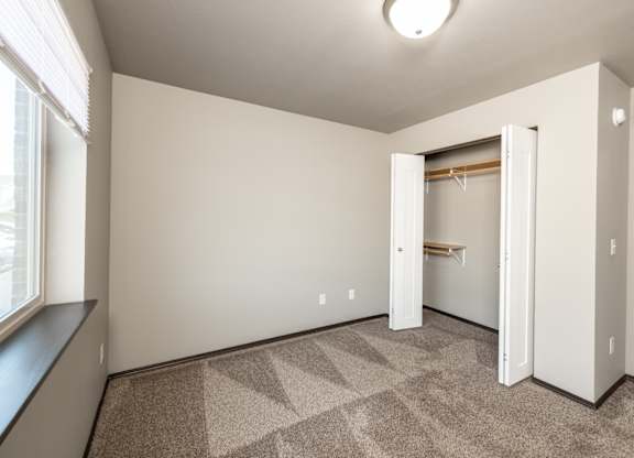 an empty room with a closet and a window