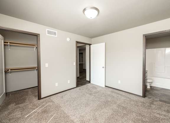 a bedroom with a closet and a bathroom with a mirrored door