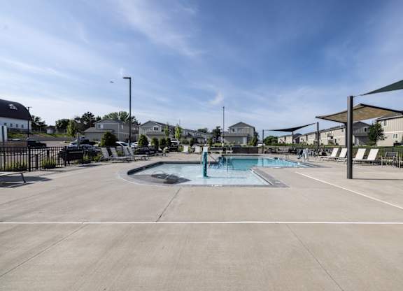 A large outdoor swimming pool with a hot tub and lounge chairs.