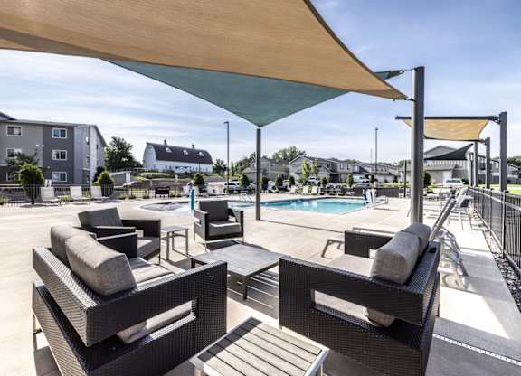 A patio with black wicker furniture and a pool in the background.