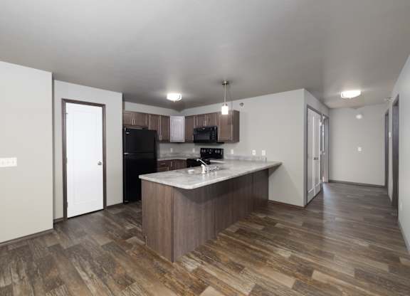 A kitchen with a wooden floor and a white ceiling.