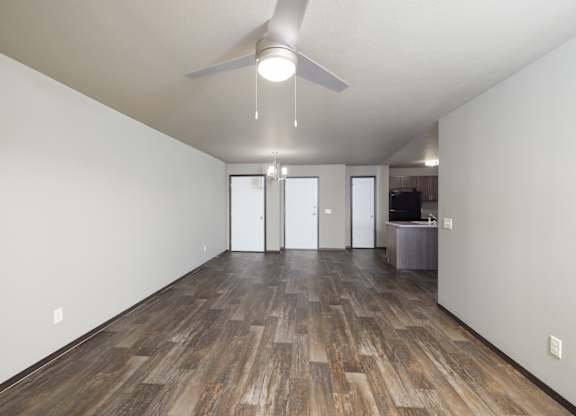 A room with a ceiling fan and wood flooring.