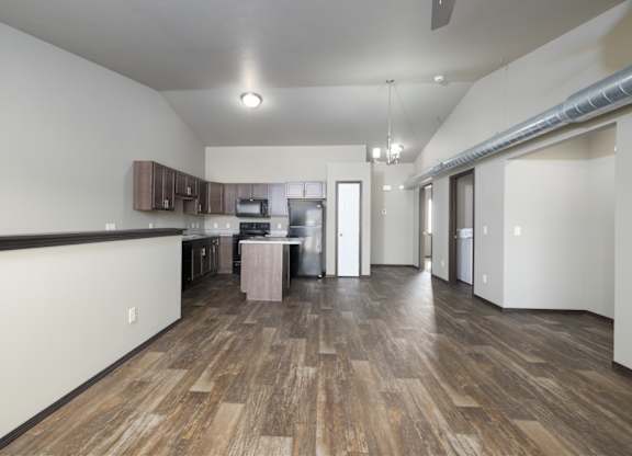 A kitchen with wood flooring and a white wall.