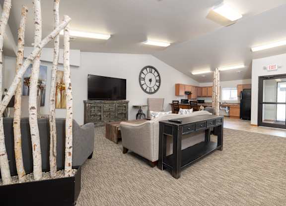 A living room with a TV, a couch, and a clock on the wall.