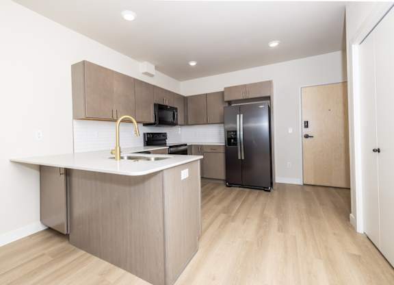 A kitchen with a refrigerator, microwave, and oven.