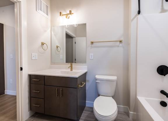 A white toilet sits in a bathroom next to a sink and a bathtub.