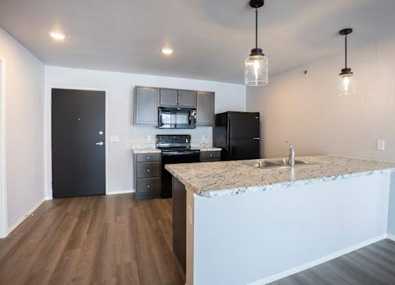 Modern open-concept kitchen and living area with black appliances.