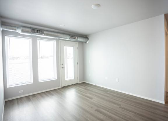 Empty living room with large, bright windows.