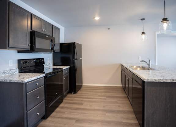 Modern open-concept kitchen and living area with black appliances.