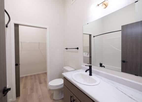 A bathroom with a toilet, sink, and mirror.