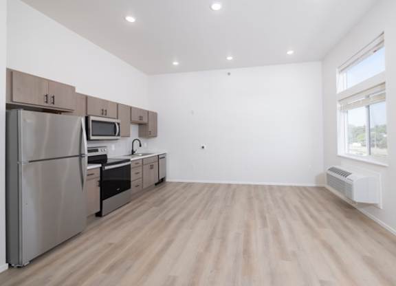 A kitchen with a refrigerator, microwave, oven, and cabinets.