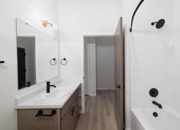 A bathroom with a sink, mirror, and bathtub.