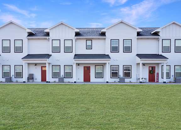 A row of white houses with red doors.
