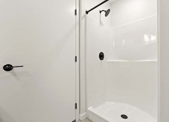 A white bathroom with a shower and a door.