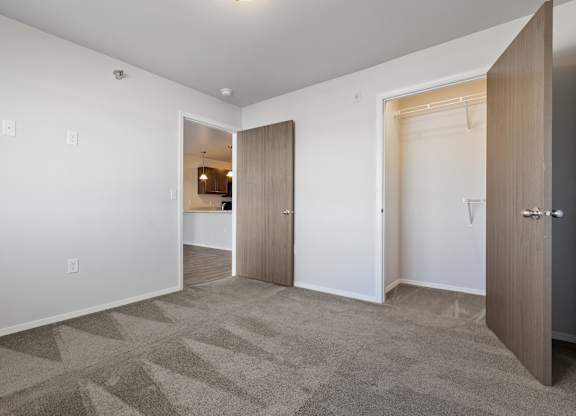 A room with a carpeted floor and a white wall with a doorway leading to another room.