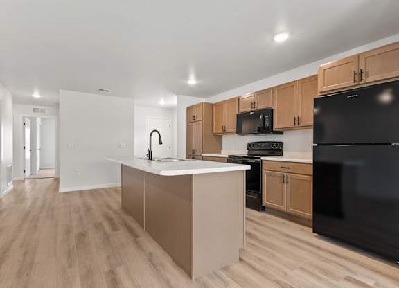 A kitchen with wooden cabinets and a black refrigerator.