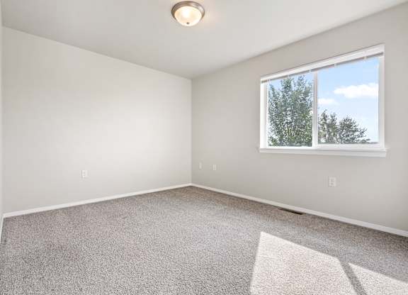 A room with a window showing trees outside.