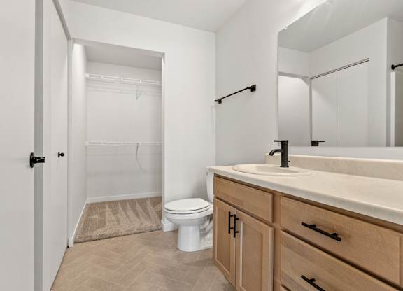 A bathroom with a toilet, sink, and a mirror.
