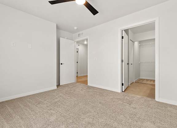 A room with a carpeted floor and a ceiling fan.