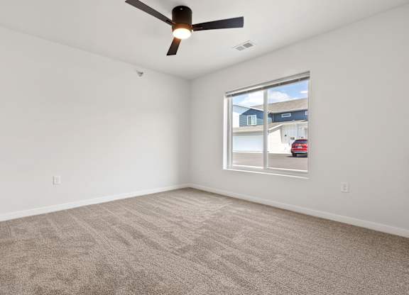 A room with a ceiling fan and carpeted floor.