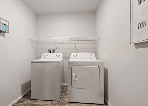 Two white washing machines in a small laundry room.