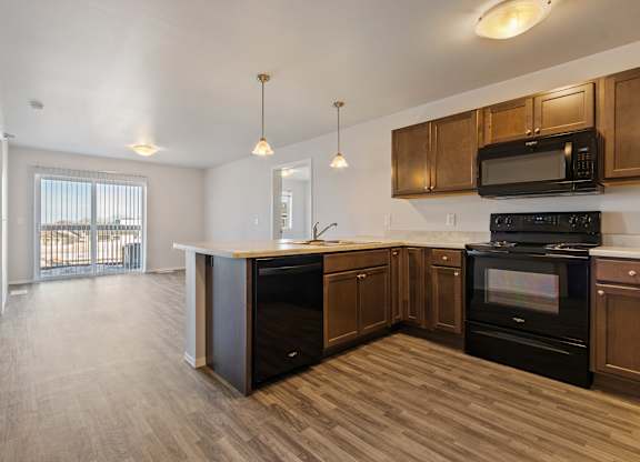 A kitchen with black appliances and wooden cabinets.