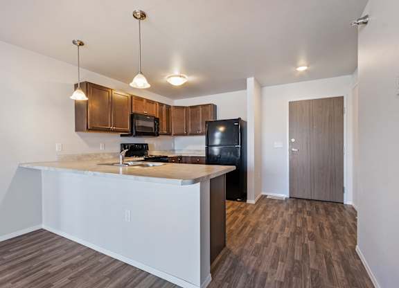 A kitchen with a black fridge and wooden cabinets.