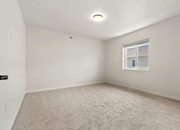 A room with a carpeted floor and a window.