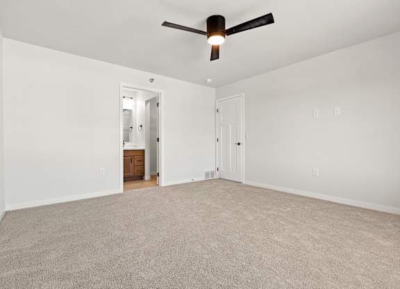 A room with a ceiling fan and carpeted floor.