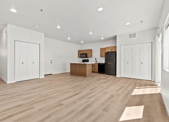 A spacious room with wooden flooring and white walls.
