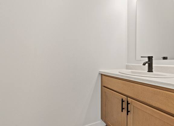 A bathroom sink with a wooden cabinet and a mirror above it.